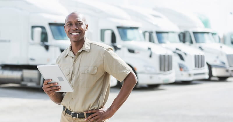 logistics manager at a trucking company smiling and holding a tablet