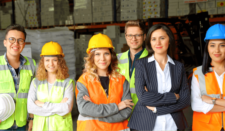 employees and manager standing in a warehouse wearing safety equipment